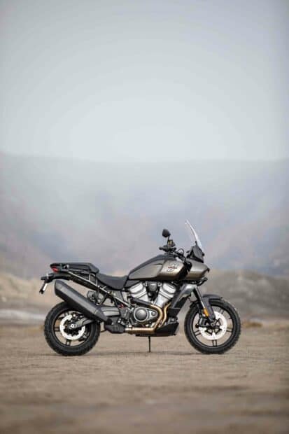 Harley Davidson Pan America 1250 adventure bike   A Harley Davidson Pan America 1250 motorcycle parked on a sandy terrain with mountains in the background