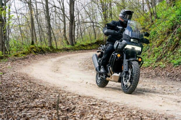 A rider on a Harley Davidson Pan America 1250 is traveling through a forest trail, 2K Desktop Wallpaper