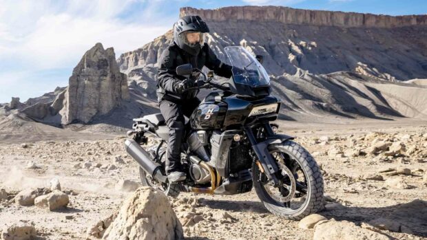 A rider on a Harley Davidson Pan America 1250 cruising through a rocky desert terrain, HD Desktop Wallpaper
