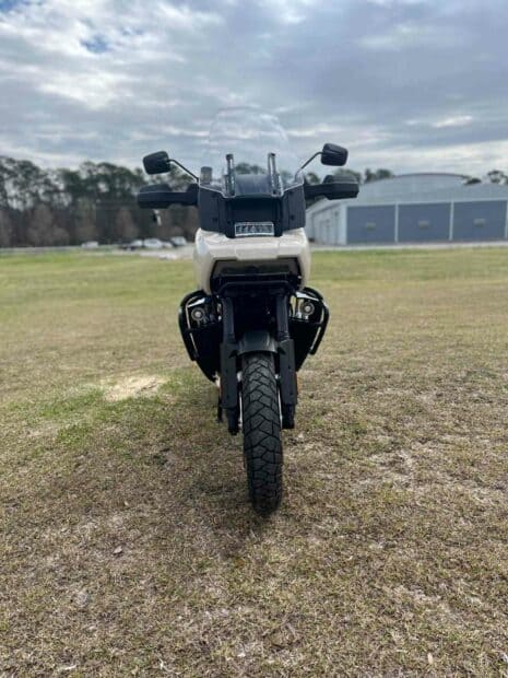 The Harley Davidson Pan America 1250 motorcycle is parked on grass with a cloudy sky in the background, HD Mobile Wallpaper