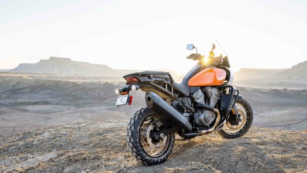 A Harley Davidson Pan America 1250 is parked on a rocky desert terrain at sunset, 4K Desktop Wallpaper
