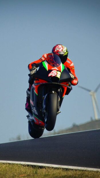 A rider on an Aprilia bike performs a high jump over a racetrack hill, HD Mobile Wallpaper