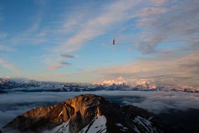 Highline Slacklining Over Mountain Peaks with Stunning Sky View Wallpaper