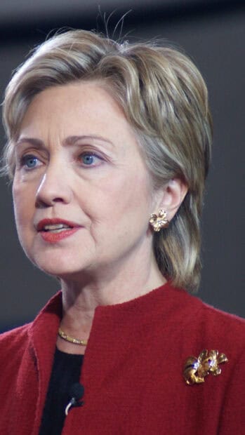 Hillary Clinton with a red jacket and gold accessories looking focused, HD Phone Wallpaper