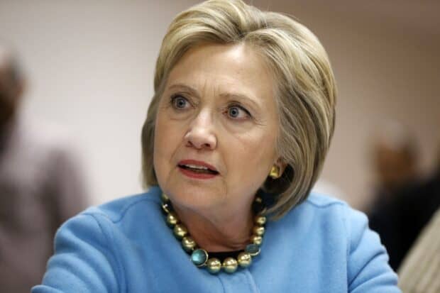 Hillary Clinton is wearing a blue outfit with a beaded necklace during a conversation, HD Desktop Wallpaper
