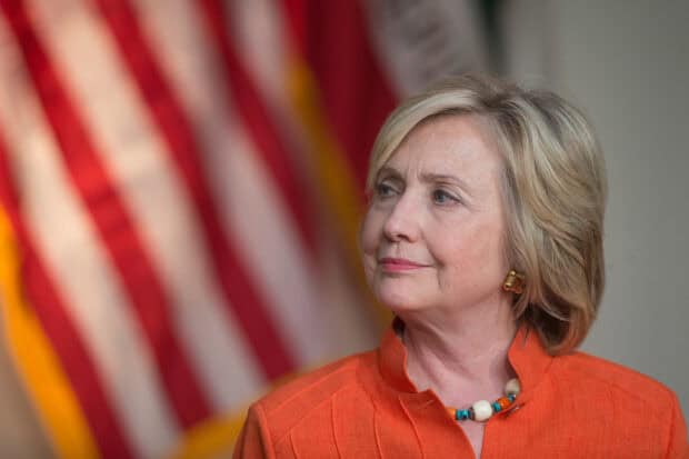 Hillary Clinton is looking to the side with the American flag in the background, HD Desktop Wallpaper