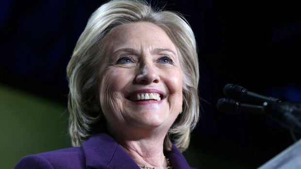 Hillary Clinton is smiling while speaking at an event with microphones in front of her, HD Desktop Wallpaper