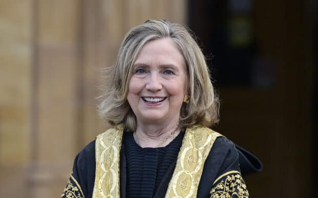 Hillary Clinton is smiling warmly wearing a black and gold robe, HD Desktop Wallpaper