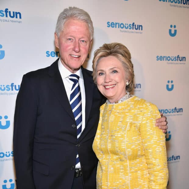 Hillary Clinton is smiling while standing next to Bill Clinton at a formal event, HD Desktop Wallpaper