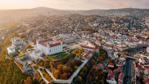 The Bratislava cityscape shows the historic castle and surrounding buildings during a warm sunset, HD Desktop Wallpaper