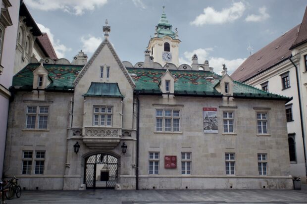 A historic building with a green tiled roof and clock tower in Bratislava showcasing architectural details, 2K Desktop Wallpaper