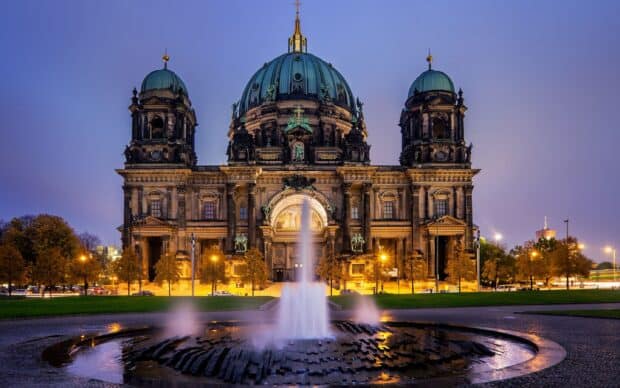 A historic cathedral with illuminated fountains at dusk, 2K Desktop Wallpaper