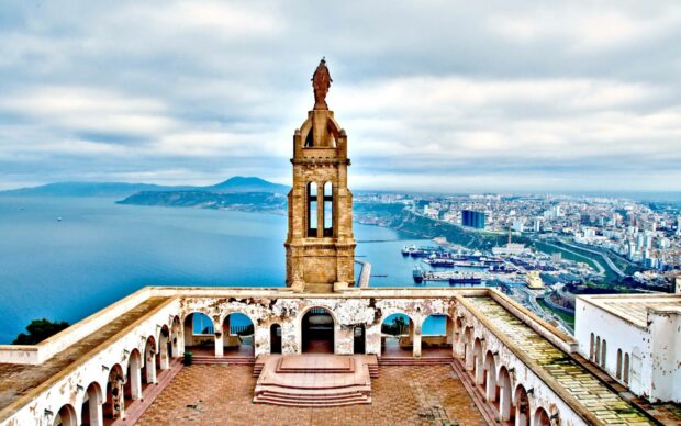 A historic monument overlooks the coastline and urban area in Algeria showing detailed architecture and sea views, 2K Desktop Wallpaper