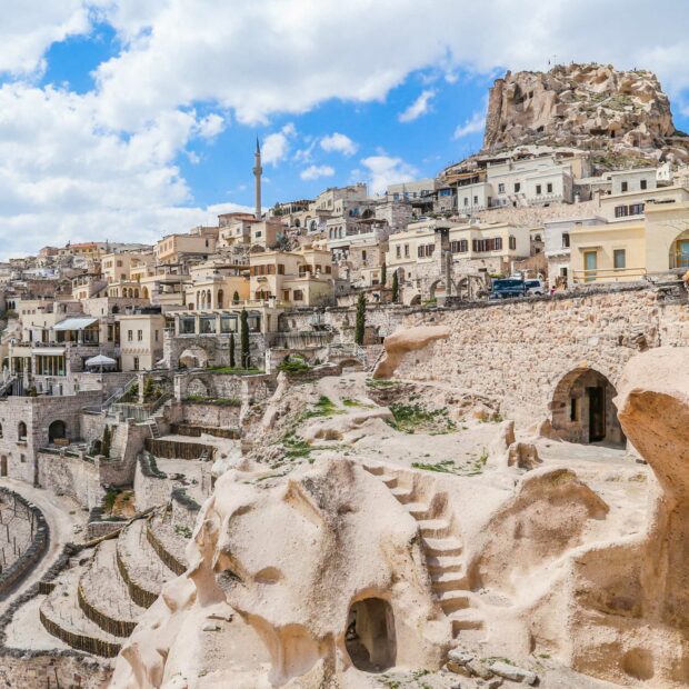 The historic town in Cappadocia shows ancient stone buildings under a partly cloudy sky, HD Desktop Wallpaper