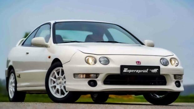 A white Honda Integra coupe is shown parked on an open road under a cloudy sky, HD Desktop Wallpaper