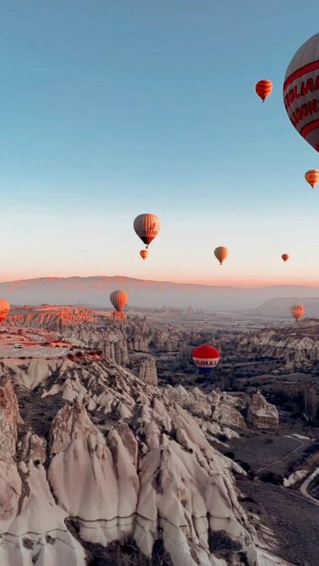 A scenic view of hot air balloons flying above the unique rock formations in Cappadocia during sunrise, HD Mobile Wallpaper