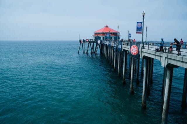 Huntington Beach Pier Overlooking Calm Ocean Waters with Visitors and Blue Sky Wallpaper