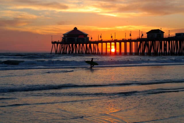 Huntington Beach sunset with pier and surfer silhouette ocean waves wallpaper