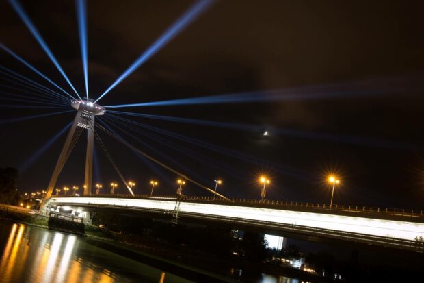 The illuminated bridge with beams of light highlights the night skyline of Bratislava in this image, HD Desktop Wallpaper