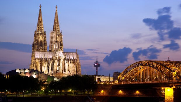 The illuminated cathedral and city skyline are shown during twilight, 4K Desktop Wallpaper