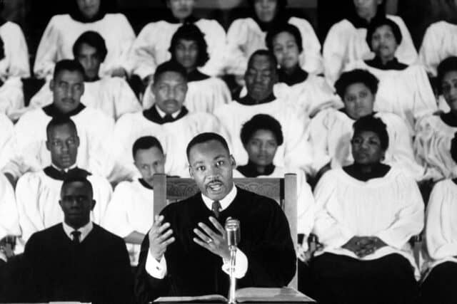 Inspiring Martin Luther King Jr Delivering A Speech With Choir Background