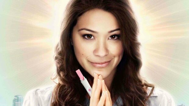 The image shows Jane The Virgin holding a pregnancy test with a hopeful expression and radiant background, HD Desktop Wallpaper