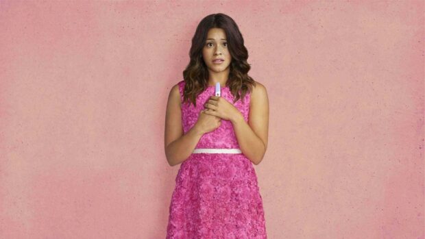 Jane The Virgin Wallpapers showcasing a woman in a pink dress holding a pregnancy test with a worried expression, HD Desktop Wallpaper