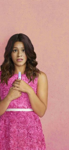 A woman in a pink dress looks worried while holding a pregnancy test against a pink background in Jane The Virgin, 2K Phone Wallpaper
