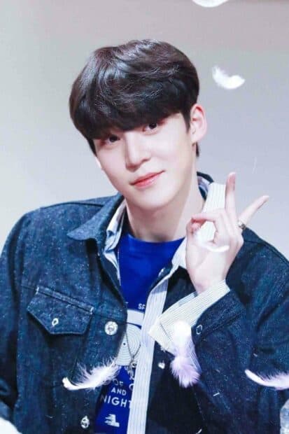 A young man named Jeong Yun Ho is smiling and posing with floating feathers around him, HD Phone Wallpaper