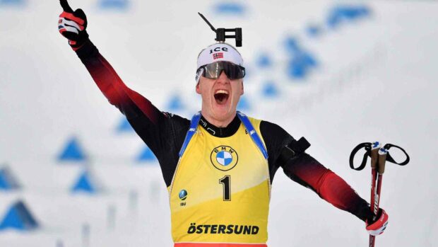 Johannes Thingnes celebrating a biathlon victory with raised arm and ski poles, HD Desktop Wallpaper