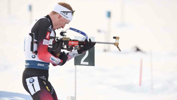 Johannes Thingnes focuses on shooting at the target during a biathlon event in the snow, HD Desktop Wallpaper