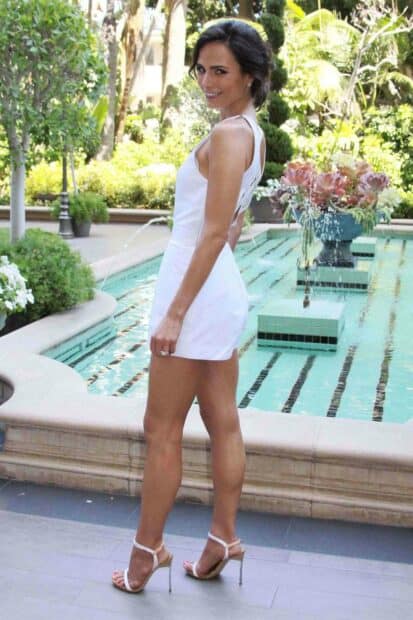 Jordana Brewster is standing by a pool wearing a white dress and high heels smiling at the camera, HD Mobile Wallpaper