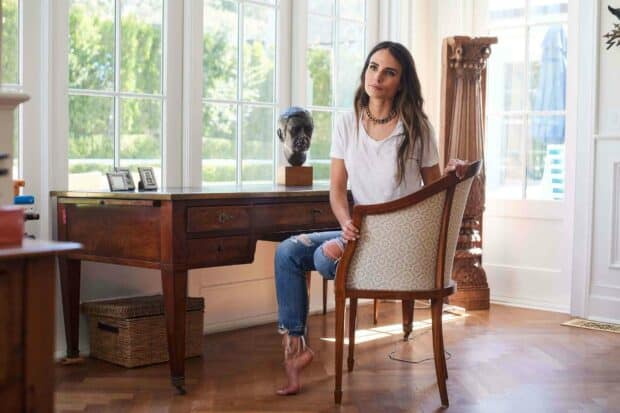 Jordana Brewster is sitting barefoot on a chair in a bright room with a wooden desk and large windows behind her, HD Desktop Wallpaper