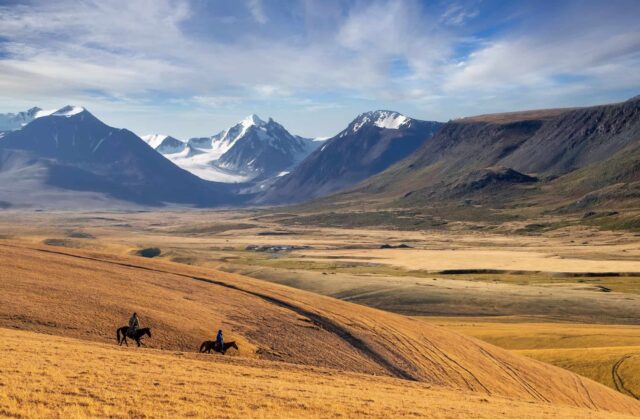 Kazakhstan Landscape Serenity With Mountains And Riders Wallpaper