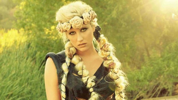 Kesha looks directly at the camera with a floral headband and braided hair in an outdoor setting, HD Desktop Wallpaper