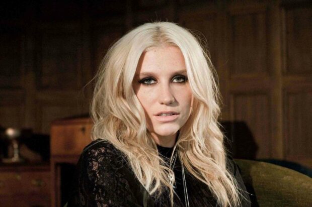 The image shows Kesha with blonde hair and smoky eye makeup sitting indoors, HD Desktop Wallpaper