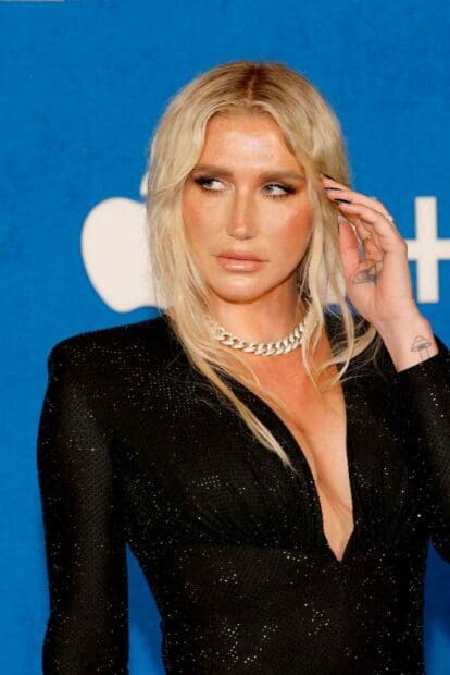 Kesha is wearing a black sparkling dress with a silver chain necklace against a blue background, HD Mobile Wallpaper