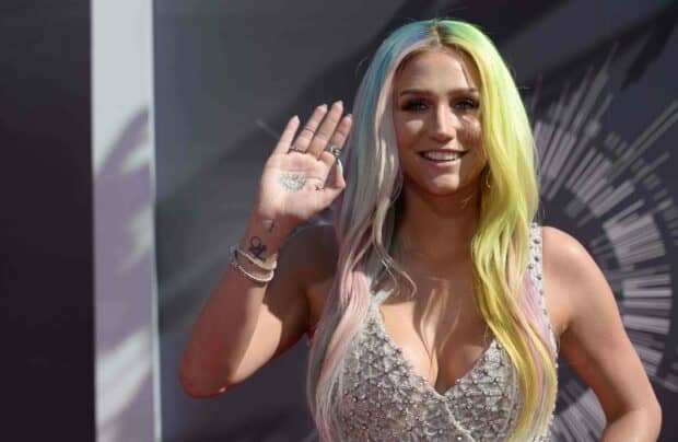 Kesha with colorful hair and a hand tattoo smiling and waving, 2K Desktop Wallpaper