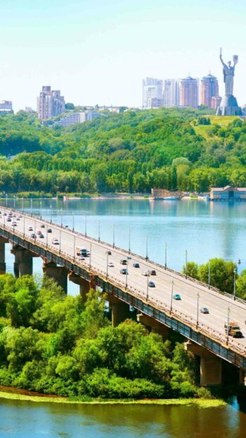 A bridge crosses the river in Kiev with lush green trees and tall buildings in the background showcasing Ukraine wallpapers, HD Phone Wallpaper