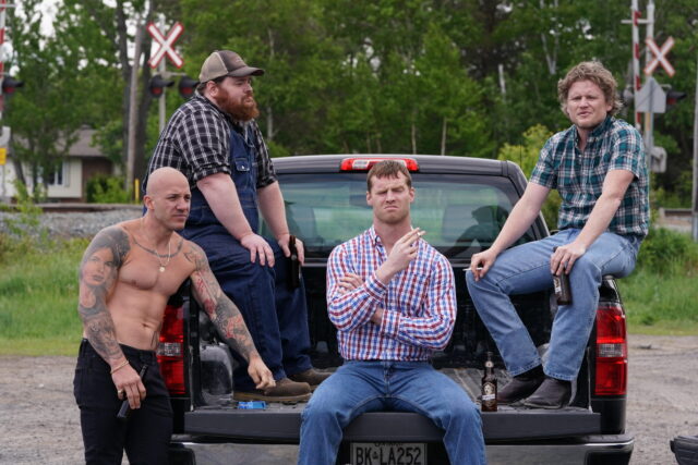 Letterkenny TV Series Characters Relaxing On Truck Tailgate In Rural Setting Wallpaper