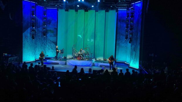 A concert scene showing a band playing on stage with green and blue lights and an audience watching, 4K Desktop Wallpaper