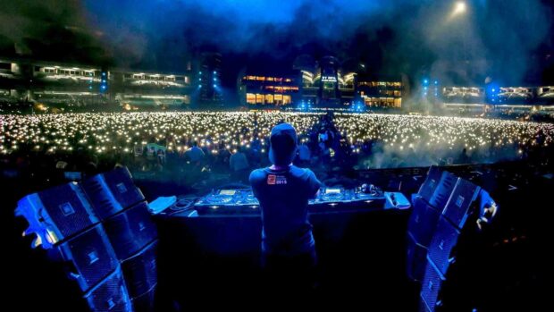A DJ is performing live at a concert with an audience holding up lights, HD Desktop Wallpaper