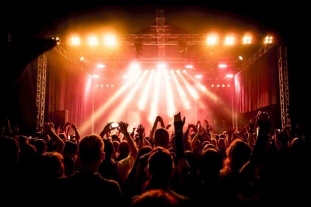 A lively concert crowd enjoying a live music event with bright stage lights and raised hands, 2K Desktop Wallpaper