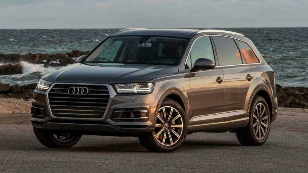 A silver Audi Q7 drives along a rocky coast under a cloudy sky, HD Desktop Wallpaper