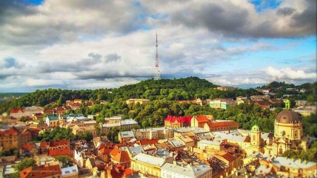 A scenic view of Lviv city with its historic buildings and a green hill in Ukraine, HD Desktop Wallpaper