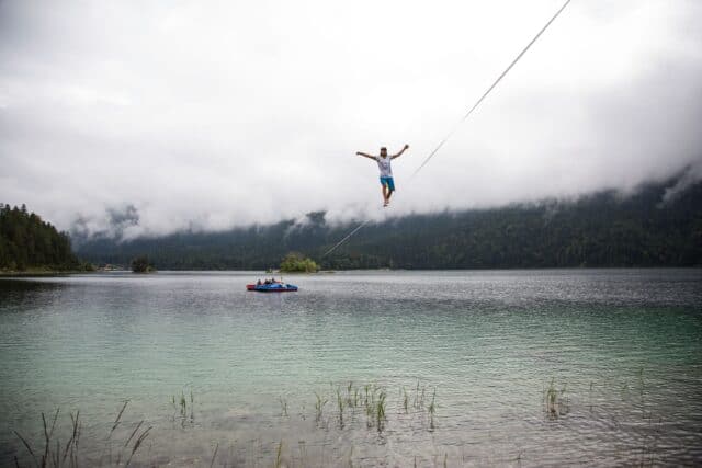 Man Balancing on Highline Above Calm Lake with Foggy Mountain Background Slacklining Wallpapers