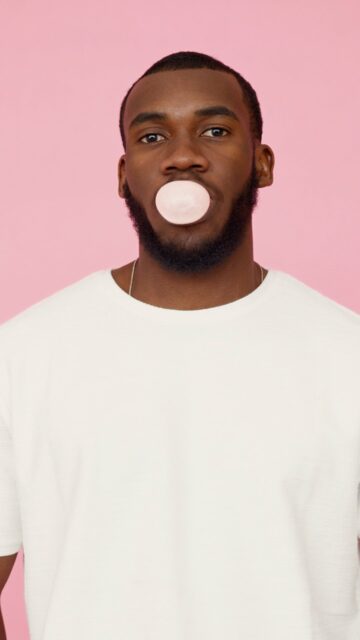 Man Blowing Bubblegum In Pink Background Wallpaper