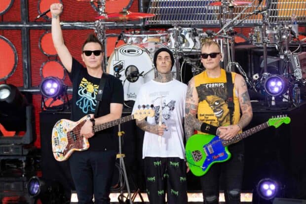 Mark Hoppus and his band members perform live on stage with guitars and drums in the background, HD Desktop Wallpaper