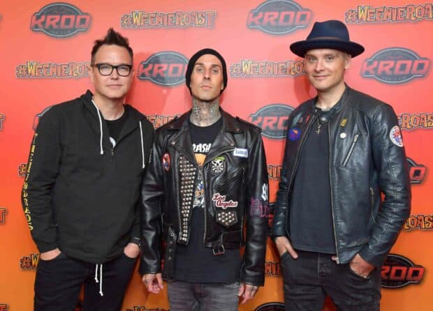 Mark Hoppus and his band members standing together at a music event with a red backdrop, HD Desktop Wallpaper