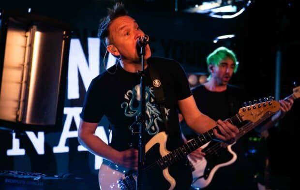 Mark Hoppus passionately sings and plays guitar during a live concert performance, HD Desktop Wallpaper